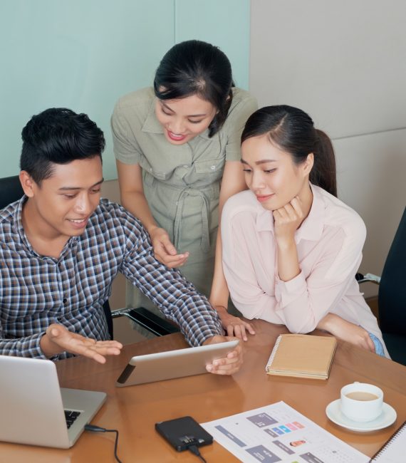 Young Asian business people discussing information on tablet computer
